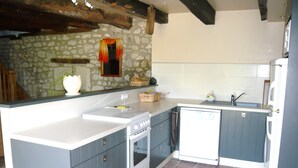A kitchen with a stone wall, a white stove, a sink, and a dishwasher. - Luxury gite for adult couples, peaceful, open views, large swimming pool (Boisse)