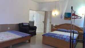 A hotel room with two single beds, a massage chair, a ceiling fan, and a wall-mounted TV. - Kumasi Atonsu Dompoase Cozy Apartment (Kumasi)
