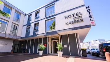 Hotel Kaspar's exterior features a brick and plaster facade with a welcoming entrance and lush greenery.