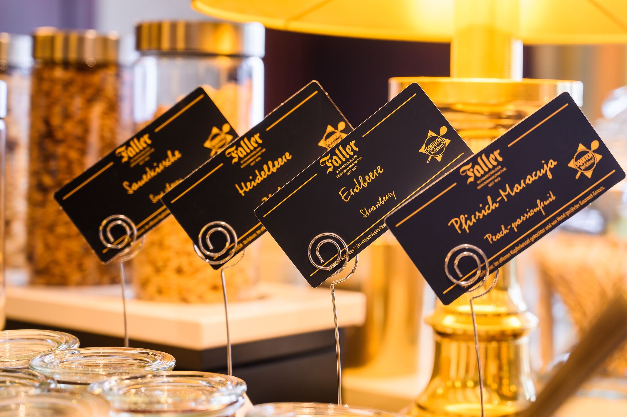 A display of black cards with gold text, each labeled with a different type of fruit preserve.