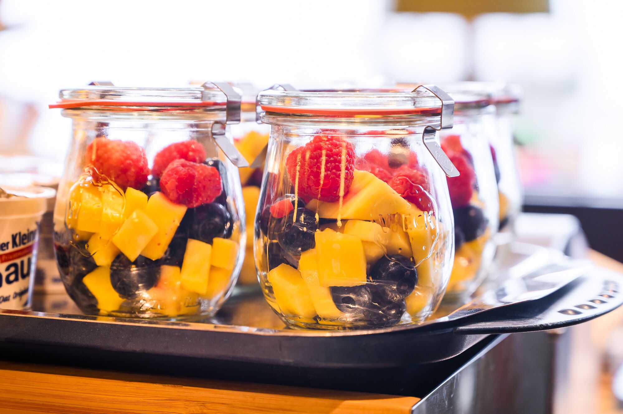 Una bandeja con tres frascos de vidrio que contienen fruta variada.