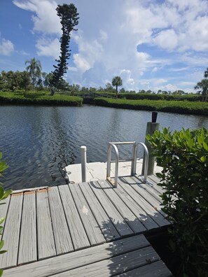 A wooden dock extending over calm water, with a metal railing and a small white structure on the dock. - Great Island Getaway! (Holmes Beach)