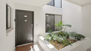 A modern entrance with a dark door, a small window, and a planter with plants and pebbles. - Great Island Getaway! (Holmes Beach)