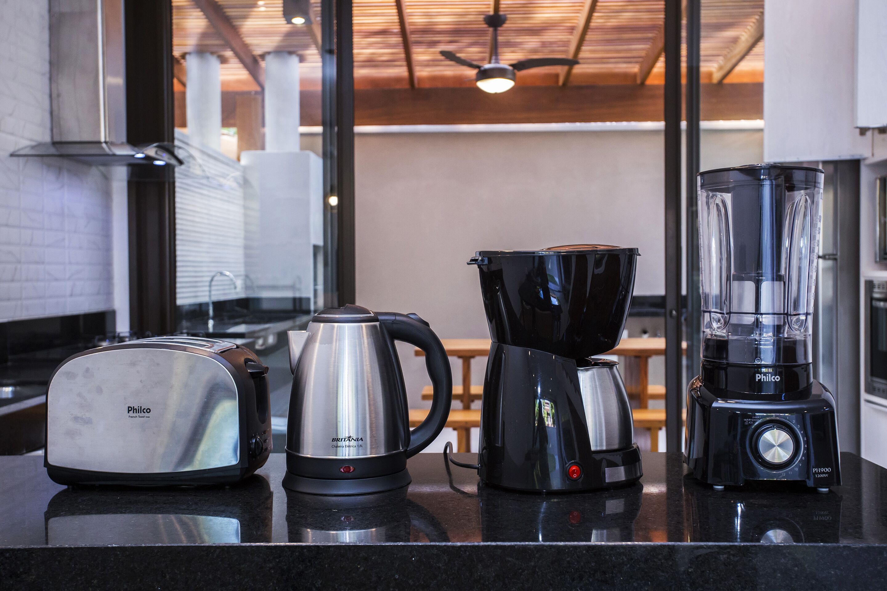 Uma bancada de cozinha com uma torradeira, chaleira e cafeteira.