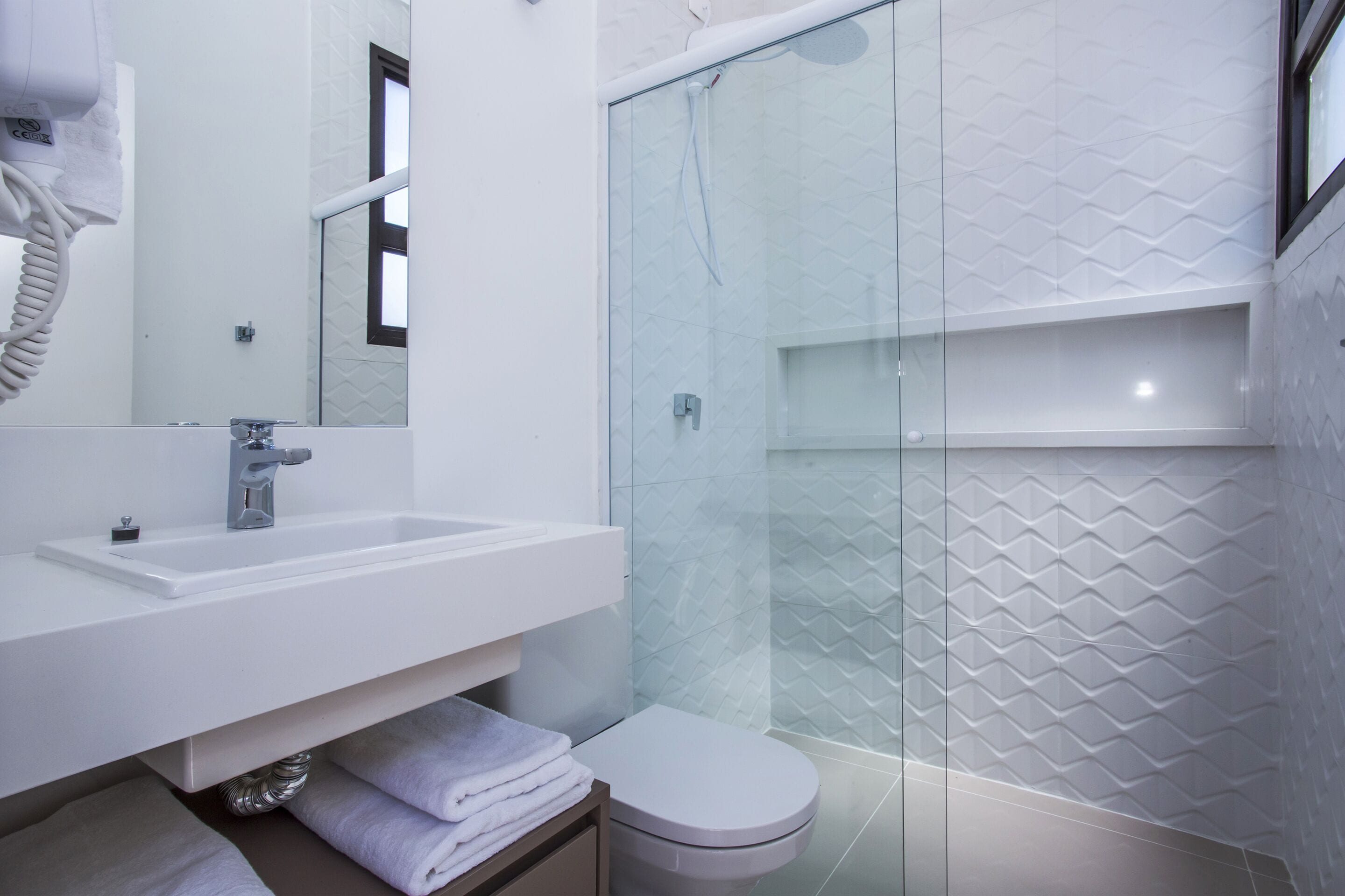 A modern bathroom with a glass-enclosed shower, a white sink, and a toilet.