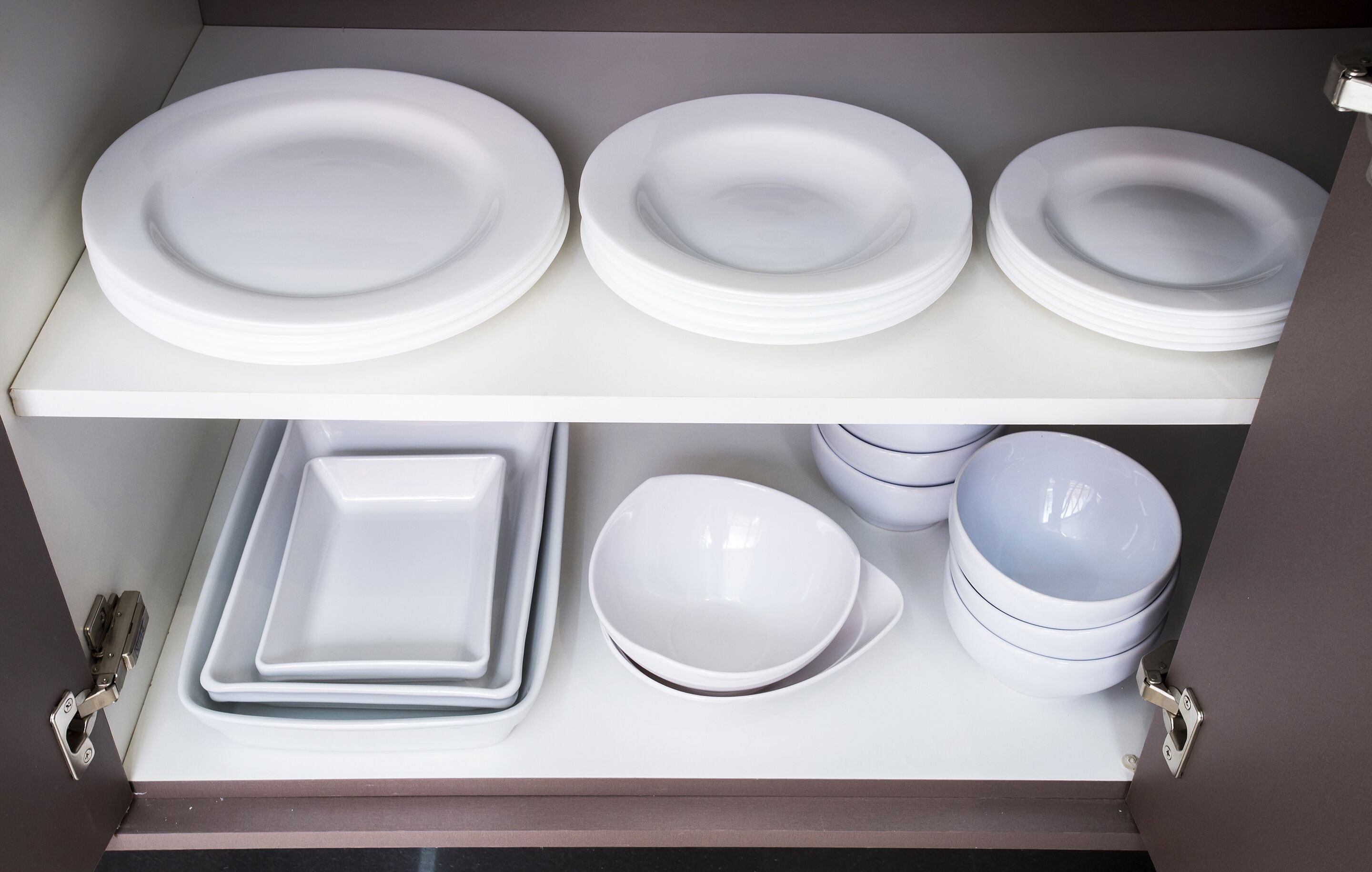A storage unit with white plates and bowls.