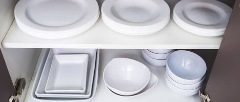A storage unit with white plates and bowls.