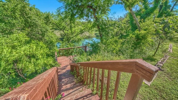 A wooden staircase leading to a natural area with a view of a body of water. - SS B11 Seele Street River Retreat (New Braunfels)