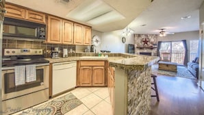 A kitchen with wooden cabinets, a microwave, stove, and a stone island. - SS B11 Seele Street River Retreat (New Braunfels)