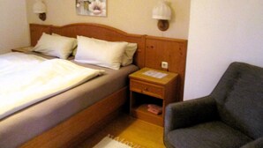 Una habitación de hotel con una cama, una mesita de noche, una silla y una lámpara de pared.