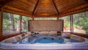 A hot tub in a wooden cabin with large windows and a view of the forest. - Spring Creek Cabin | 6BR | Hot Tub & Sauna (Fairmont Hot Springs)