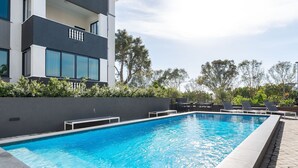 A modern building with a swimming pool, outdoor seating, and a landscaped area with trees. - Designer apartment close to the Waterfront (Cape Town)