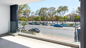 Un balcón con vista a una calle bordeada de coches y árboles.