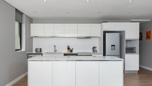 Una cocina moderna con muebles blancos, una isla central y un horno empotrado.