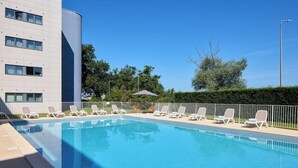 A swimming pool with lounge chairs and a modern building in the background. - Zenitude Hotel-residences Bordeaux Aeroport Merignac (Merignac)