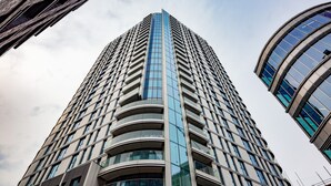 A tall, modern building with a curved facade and multiple balconies. - One Bedroom Apartment at Alie Street in Aldgate London by MySquare (London)