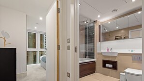 A modern bathroom with a glass shower, a white sink, and a toilet. - One Bedroom Apartment at Alie Street in Aldgate London by MySquare (London)