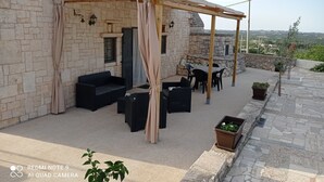 Een stenen gebouw met een houten pergola, terras en uitzicht op het landschap.