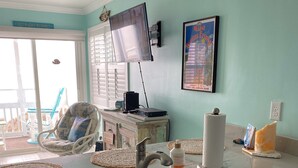 Eine Küche mit einem Spülbecken, einem Stuhl, einem Fernseher und einem gerahmten Bild an der Wand.