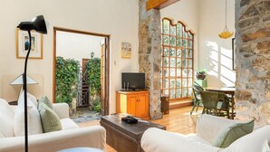 A cozy living room with a stone wall, a television on a wooden cabinet, and a dining area with a table and chairs.