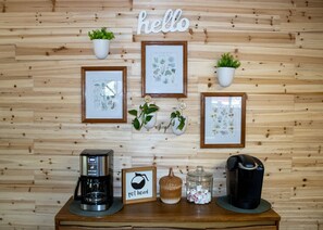 A wall with wooden paneling, a 'hello' sign, and several framed botanical illustrations.