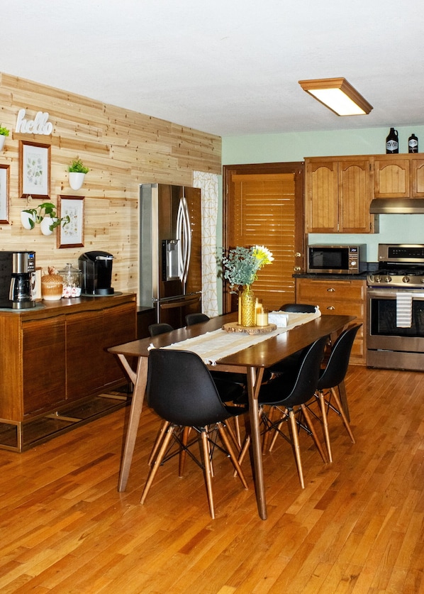 A modern kitchen with wooden cabinetry, a dining table with chairs, and a refrigerator.