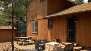 Ein Holzbau mit Außenbestuhlung, darunter ein Tisch und Stühle, und einem überdachten Bereich.