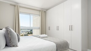 Un dormitorio con una cama grande, una ventana con cortinas y un armario.
