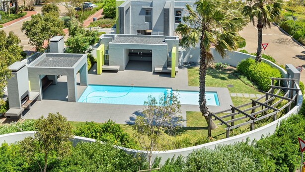 Un edificio moderno con piscina, rodeado de vegetación y palmeras.