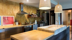Una cocina moderna con una isla central, armarios de madera, electrodomésticos de acero inoxidable e iluminación colgante.