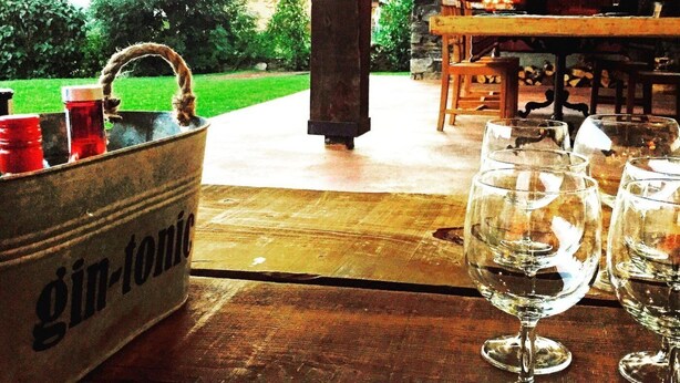 Una mesa de madera con un cubo metálico que dice 'gin-tónicos' y varias copas de vino vacías.