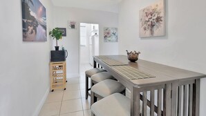A modern kitchen with a wooden table and bar stools, a ceiling fan, and artwork on the walls. - PRIME DELRAY BEACH, CHARMING 2 BEDROOM COTTAGE, PETS WELCOME  (Delray Beach)