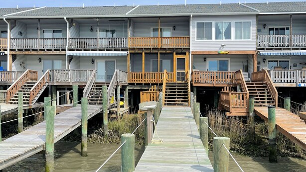 A waterfront property with multiple levels, wooden walkways, and a dock extending into the water. - Tern Inn - Water Front - Townhouse, deep water dock. LINENS AND TOWELS, (Chincoteague)