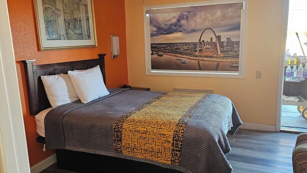 Habitación de hotel con una cama, un cuadro enmarco de un paisaje urbano y vistas a un paisaje urbano a través de una ventana.