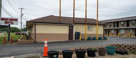 Un motel con un letrero que dice 'Indian Mound Motel', un estacionamiento con macetas y un edificio de techo marrón.