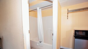 Un baño con cortina de ducha, bañera y microondas.