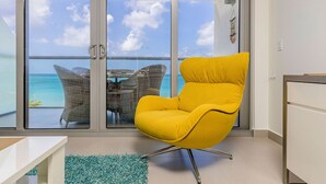 Een gele fauteuil in een moderne kamer met uitzicht op de oceaan door grote glazen deuren.