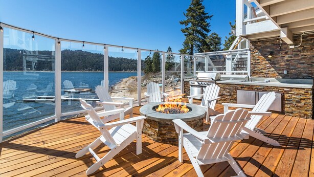 Una terrazza con un focolare, poltrone Adirondack bianche e un muro in pietra.