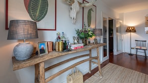A wooden console table with a lamp, books, decorative items, and a framed picture. - JOIVY Stylish 2-bed Flat w/ Terrace Near Battersea Park (London)