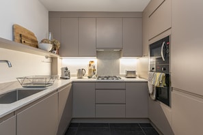 A modern kitchen with a built-in microwave, oven, and gas stove. - JOIVY Stylish 2-bed Flat w/ Terrace Near Battersea Park (London)