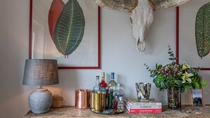 A room with a large wall-mounted skull and antlers, framed botanical prints, a variety of bottles, a lamp, and a small plant. - JOIVY Stylish 2-bed Flat w/ Terrace Near Battersea Park (London)