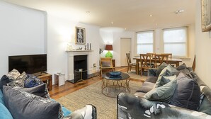Una sala de estar con sofá, televisión, chimenea, mesa de comedor y sillas.