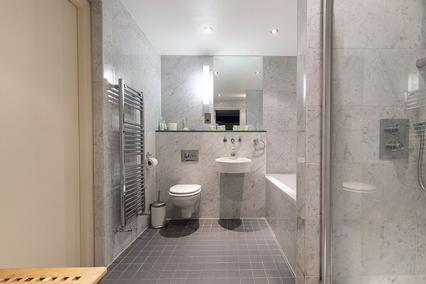 Une salle de bain moderne avec une douche à parois de verre, des toilettes, un lavabo et un miroir.