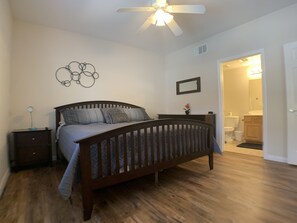 A bedroom with a wooden bed, a nightstand, a wall-mounted mirror, and a ceiling fan. - Desert Diamond Retreat by Mesquite Vacation Rentals: Pet Friendly with Community Amenities and $510 in free daily activities (Mesquite)