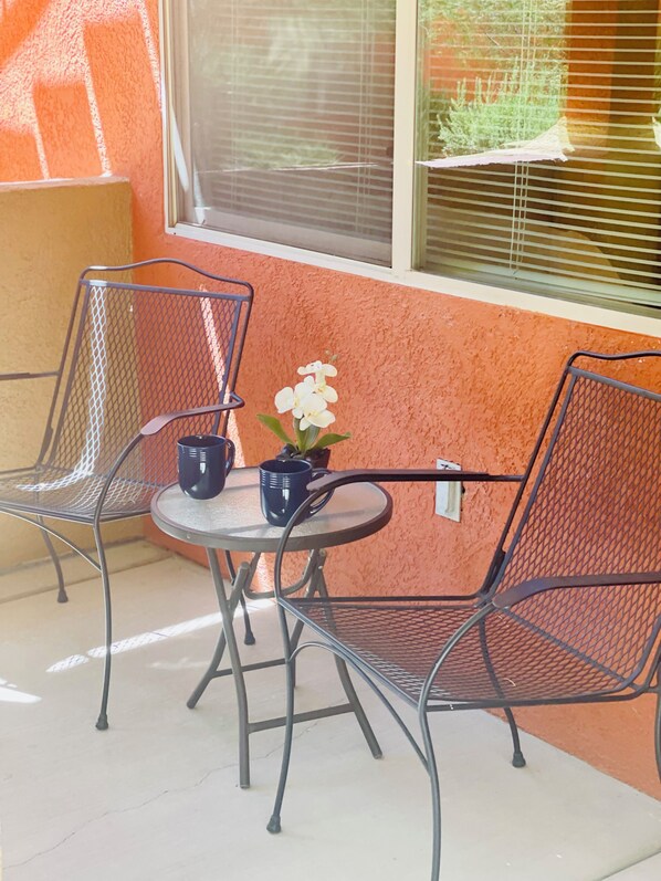 A small outdoor seating area with two metal chairs and a round table, featuring a potted plant and a black mug. - Desert Diamond Retreat by Mesquite Vacation Rentals: Pet Friendly with Community Amenities and $510 in free daily activities (Mesquite)