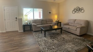 A living room with two sofas, a coffee table, a rug, a ceiling fan, and a window with blinds. - Desert Diamond Retreat by Mesquite Vacation Rentals: Pet Friendly with Community Amenities and $510 in free daily activities (Mesquite)