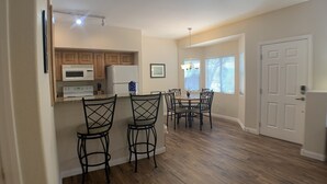 A modern kitchen with wooden cabinets, a microwave, and a refrigerator. There is a dining area with a table and chairs. - Desert Diamond Retreat by Mesquite Vacation Rentals: Pet Friendly with Community Amenities and $510 in free daily activities (Mesquite)