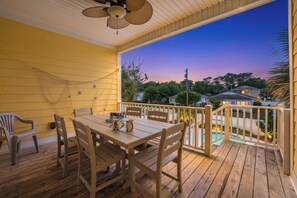A wooden deck with a table and chairs, overlooking a residential area with houses and a swimming pool. - Fun In The Sun, Luxury Beach House with Pool, Blocks from Beach (North Myrtle Beach)