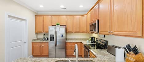A kitchen with granite countertops, stainless steel appliances, wooden cabinets, and a built-in oven.