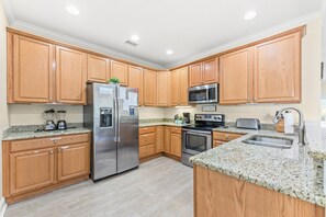 A modern kitchen with wooden cabinets, stainless steel appliances, granite countertops, and a built-in oven. - Fun In The Sun, Luxury Beach House with Pool, Blocks from Beach (North Myrtle Beach)